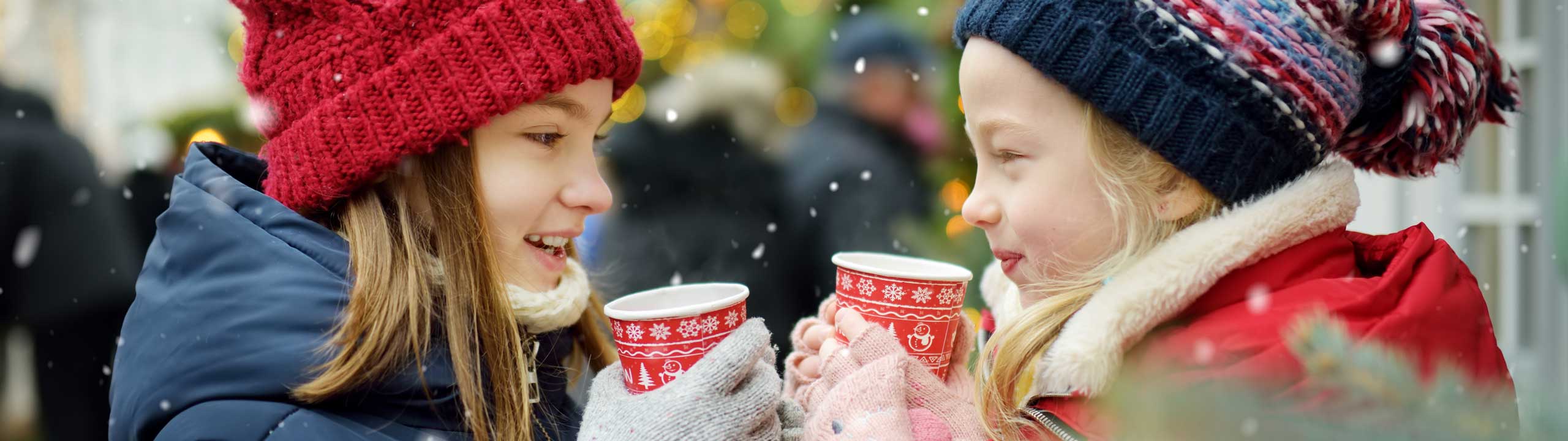 Zwei kleine Mädchen genießen heißen Punsch auf dem Weihnachtsmarkt in Ballenstedt.