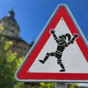 tanzender, jubelnder Ritter auf einem Warnschild vor dem Hintergrunf der Burg Falkenstein